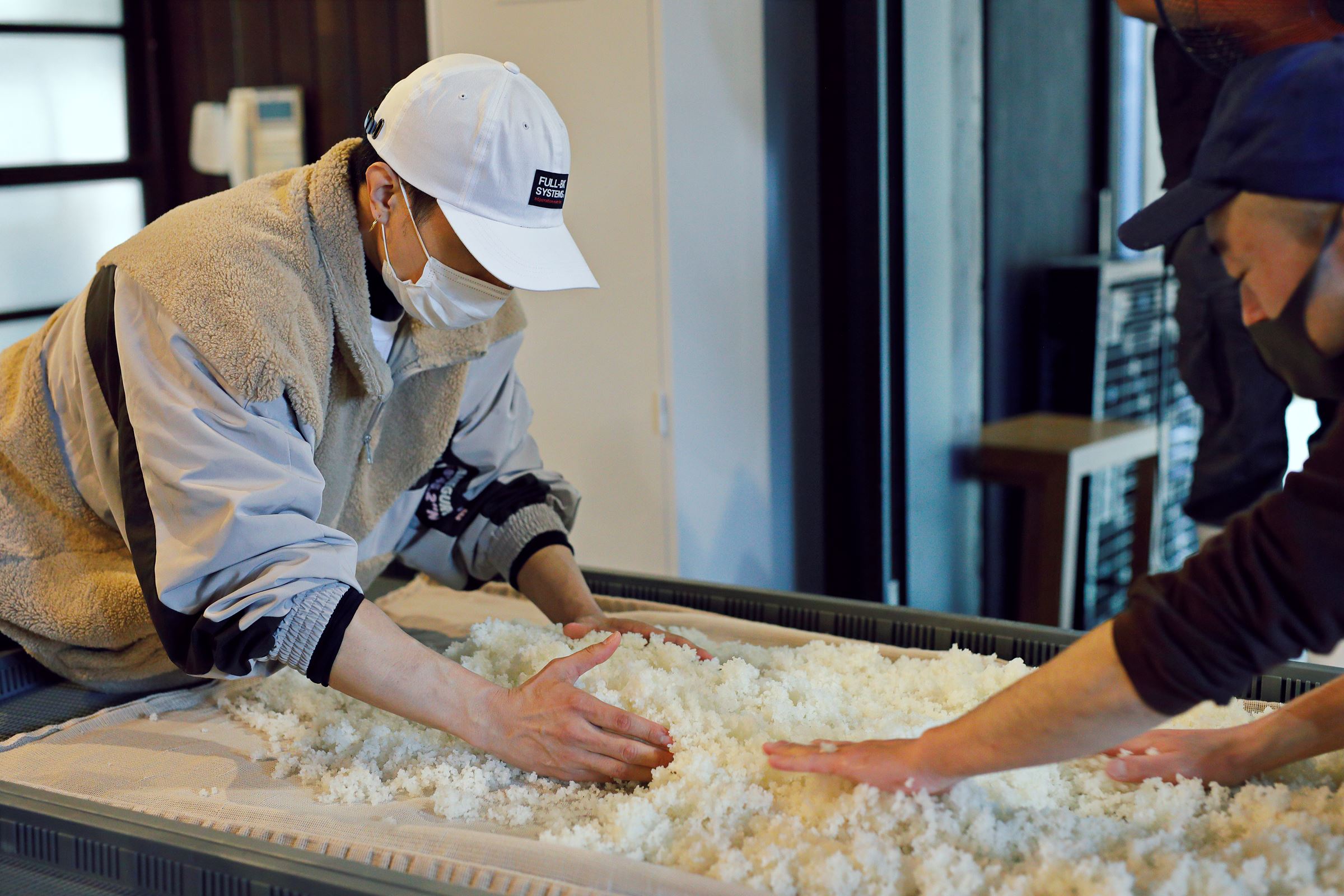 甑を使って蒸し上った米の粗熱を取るため、混ぜながら適温まで冷ましていく