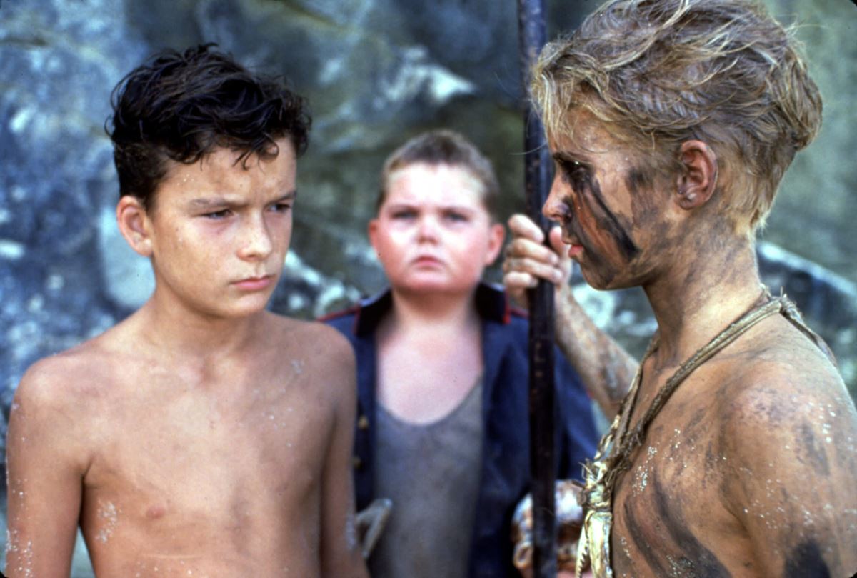 1990年に映画化された『蠅の王』のワンシーン。『十五少年漂流記』は無人島に漂流した少年たちが力を合わせて生き抜いていく物語だが、同じく無人島に置き去りにされる『蠅の王』の少年たちは、暴力的になった一部が力をもったことで悲劇的な展開に。