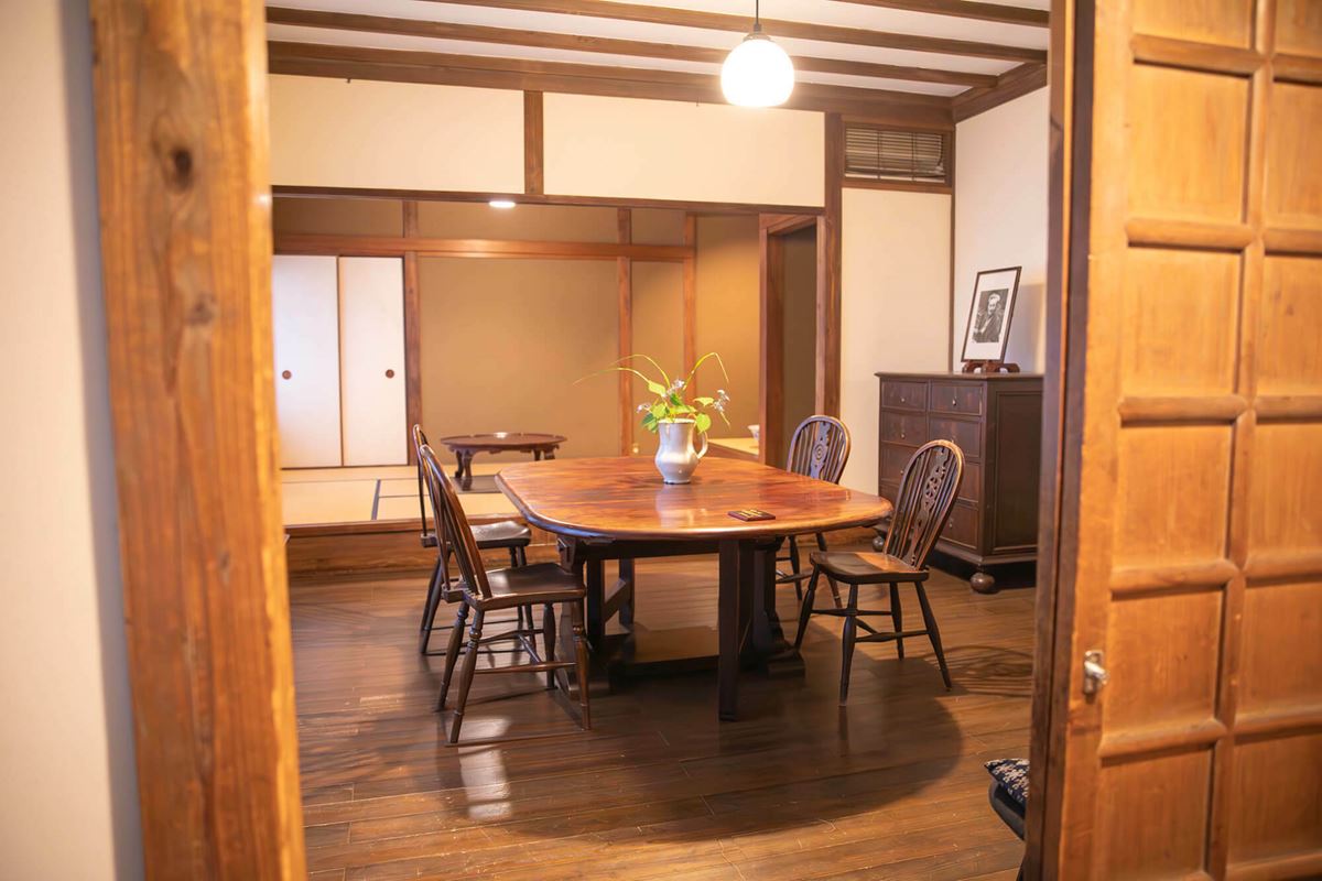 ゲートレッグテーブルが置かれた板張りの洋室と、一段上がったところに和室が設けられている和洋折衷の食堂